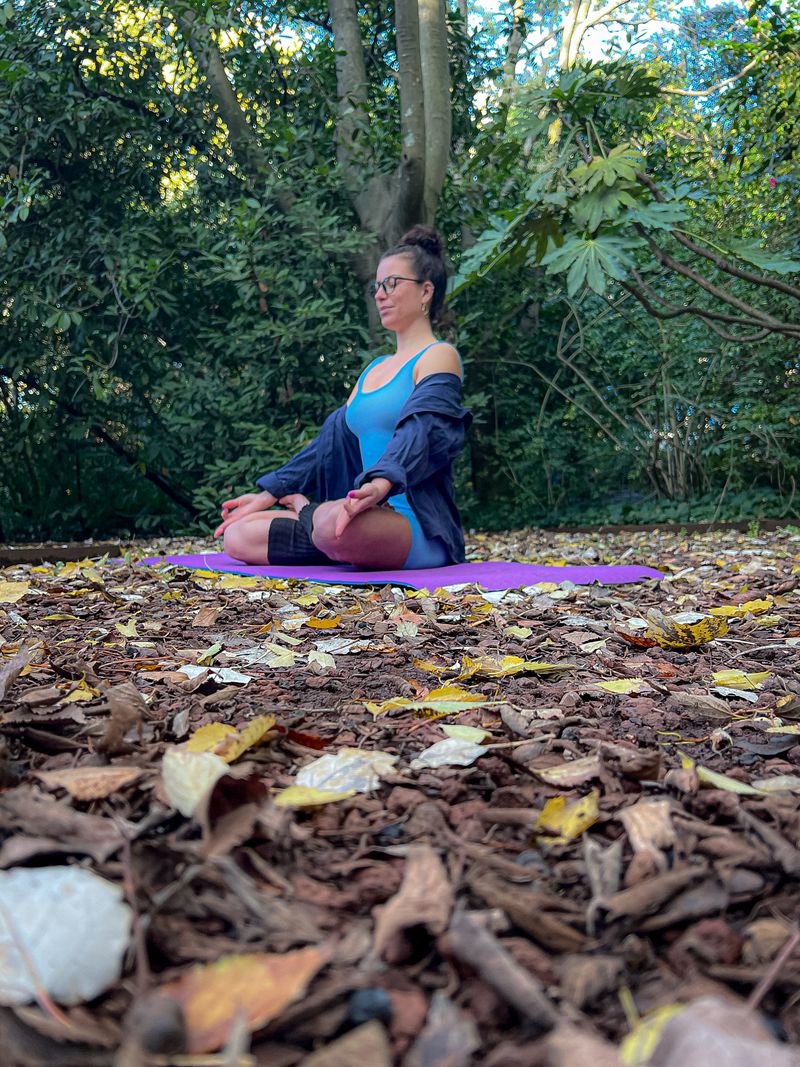 Jéssica Juttel meditando sobre o tapete Balance roxo, num bosque